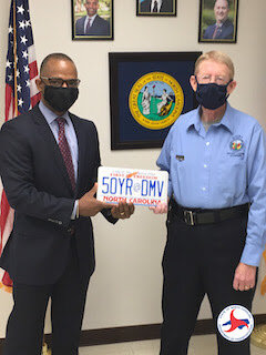   DMV Commissioner Torre Jessup, left, presents Johnny Southard with a vanity plate for 50 years of dedication to NCDMV.  