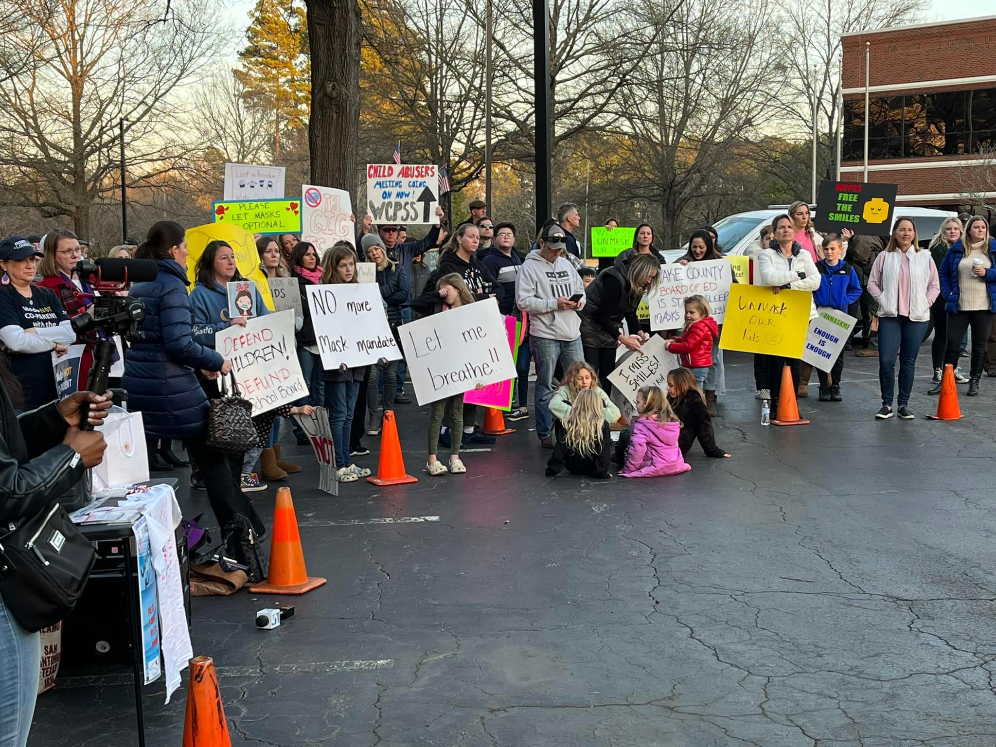   image attached of parents and opponents of mask mandates for children demonstrating outside the WCPSS meeting. Image from Carolina Teacher’s Alliance  