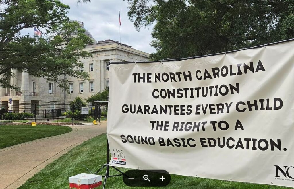  Outside the North Carolina State Capitol, a banner reminds lawmakers and the governor of their obligation to invest in the state’s public schools. (Photo: Clayton Henkel/NC Newsline) 